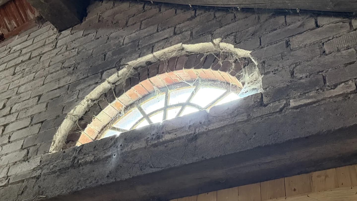 Altes Sprossenfenster im Backsteingiebel, Sinnbild für verdeckte Mängel beim genauen Prüfen
